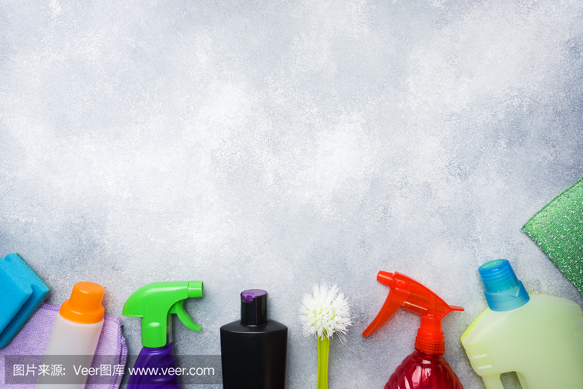 瓶子與洗滌劑,刷子和海綿在混凝土背景。色彩鮮艷的清潔產(chǎn)品。家庭清潔的概念。俯視圖,復(fù)制空間。